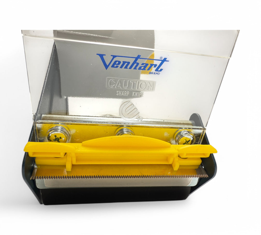 Close-up of 100mm pistol grip tape dispenser blade with serrated edge and safety guard for clean cutting